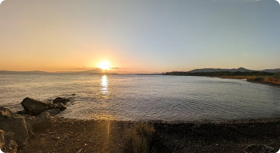 Sunset over the sea from the rocky shore at Playa Raya